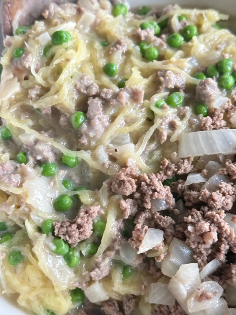 A close-up of creamy garlic spaghetti squash with ground beef and peas.