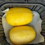 Two spaghetti squash halves turned over in an air fryer basket.