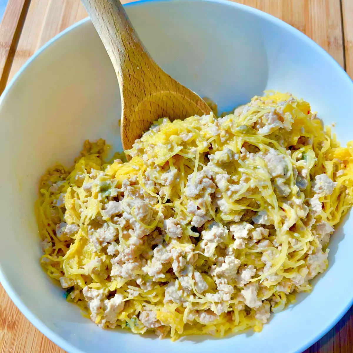 A large white bowl of ground turkey spaghetti squash with a creamy spicy sauce.