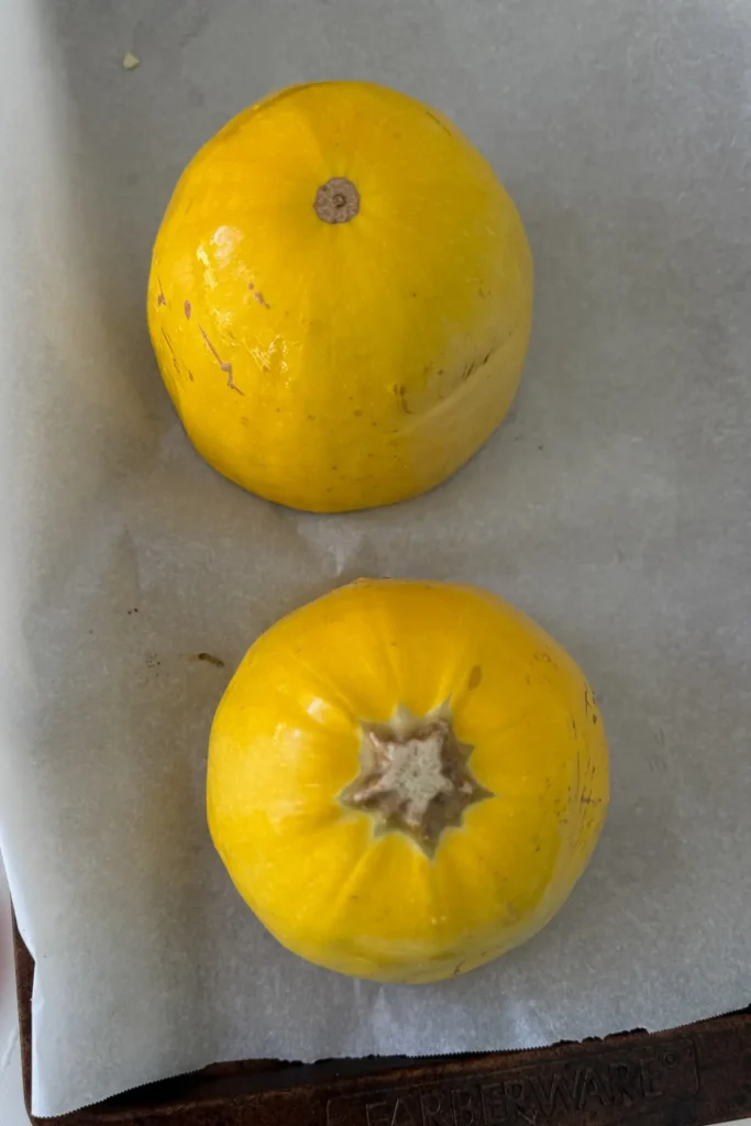 A bird-eye view of two spaghetti squash halves on a baking sheet lined with parchment.