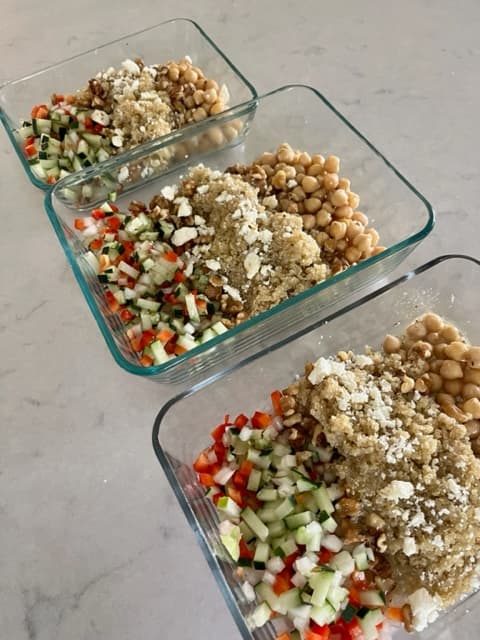 Quinoa cucumber chickpea salad portioned out in storage containers for low calorie high protein meal prep.