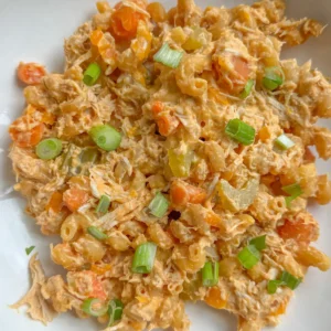 A plate of buffalo chicken pasta with cottage cheese, garnished with green onions.