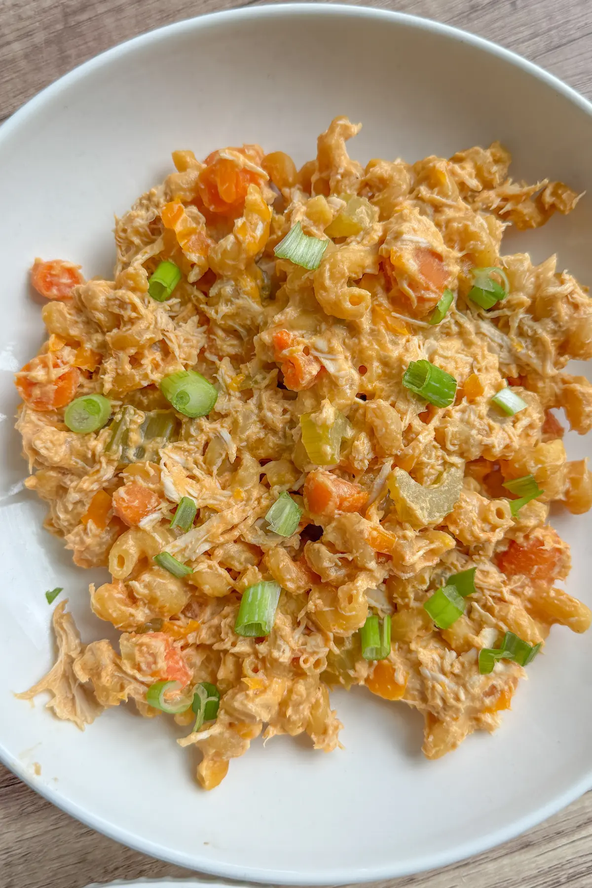 A plate of buffalo chicken pasta with cottage cheese, garnished with green onions.