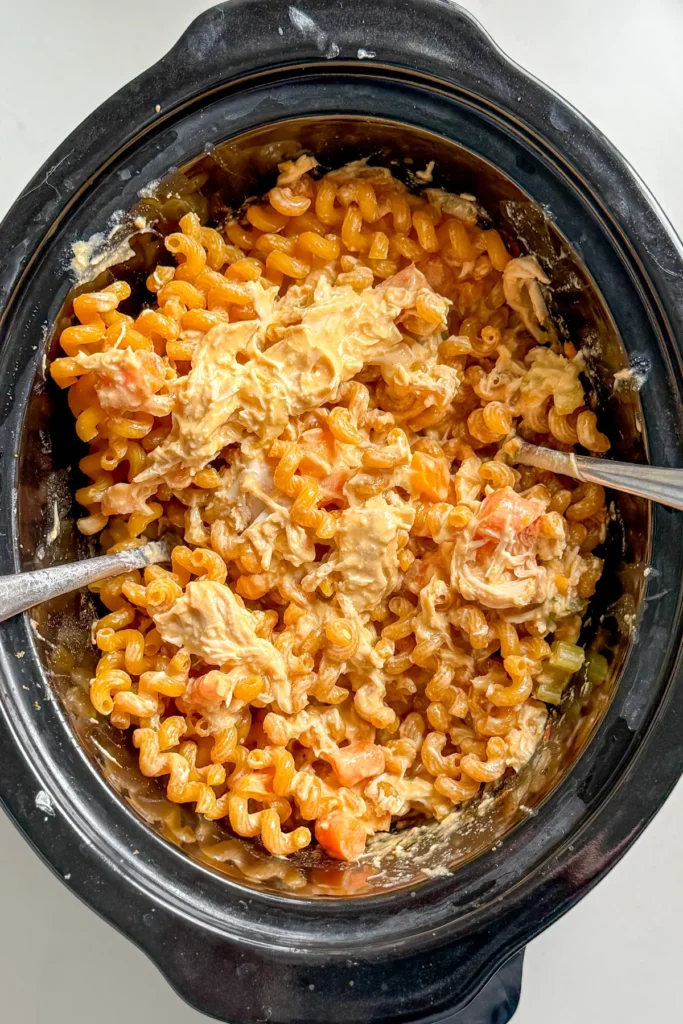 Adding the pasta noodles to the crockpot after the chicken is cooked.