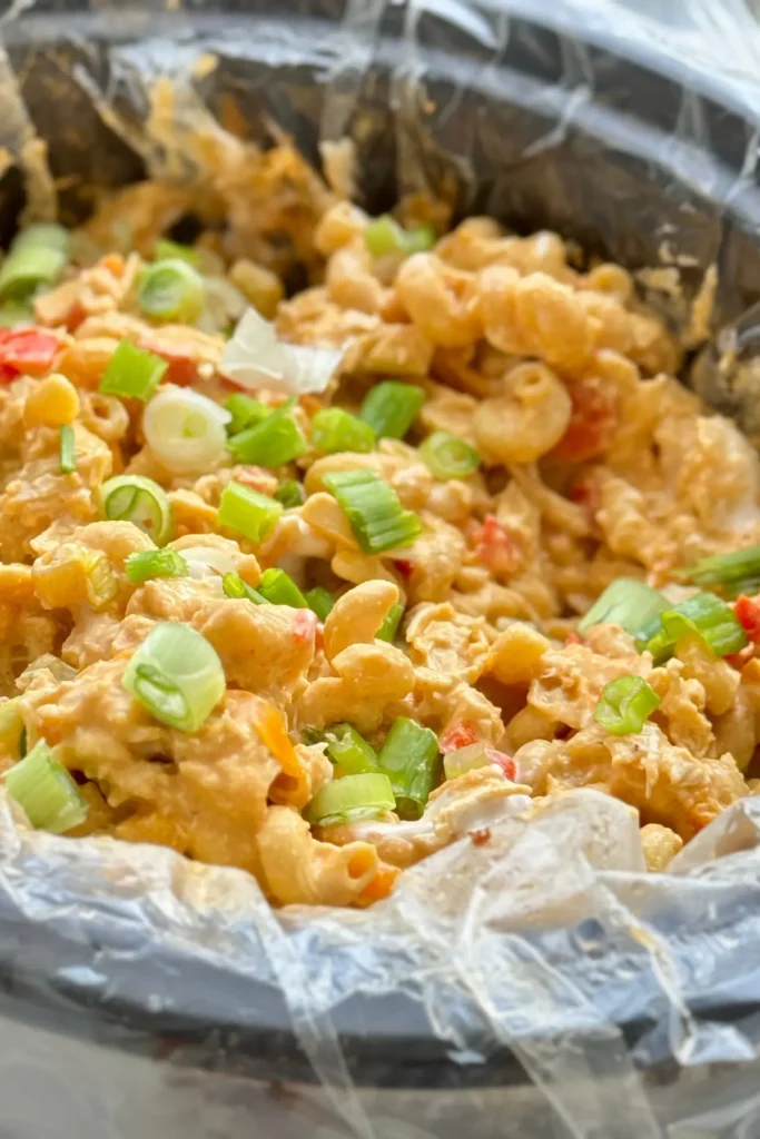 A close-up of a slow cooker with cooked buffalo chicken pasta in it.