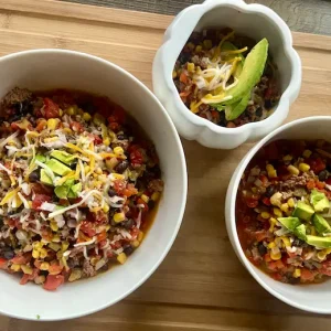 Mexican Chili in a bowl topped with shredded cheese and avocado