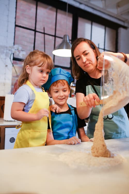 A mother cooking with her kids in the kitchen.