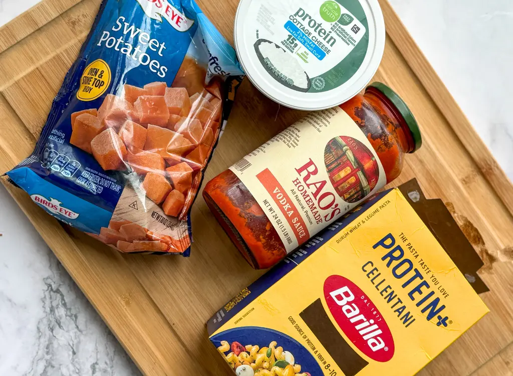 A box of Barilla Protein Plus noodles next to Rao's pasta sauce, a carton of cottage cheese, and frozen sweet potatoes.
