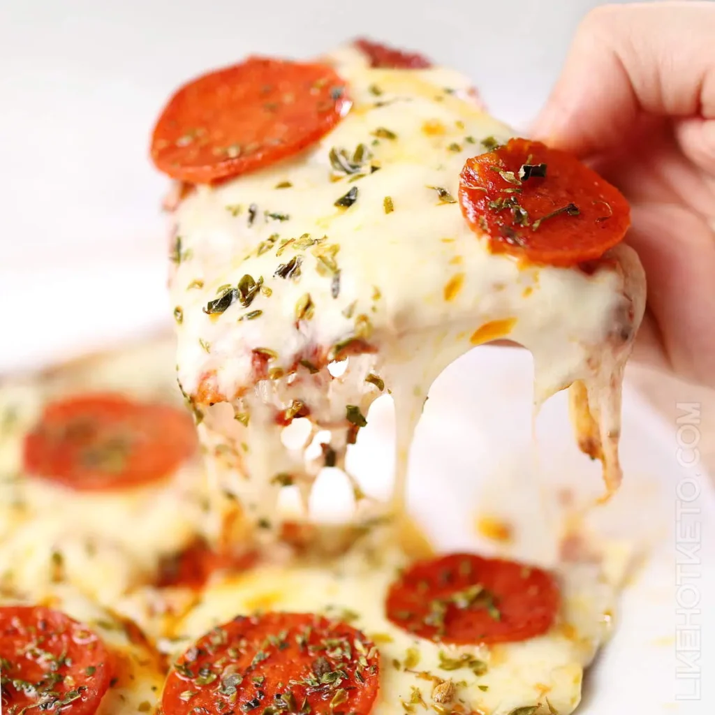 Someone holding an air fryer tortilla pizza in their hands next to a plate of more pizza.