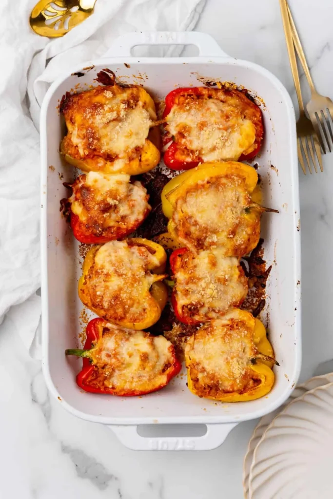 Ground chicken stuffed peppers with cheese on top in a baking dish right out of the oven.