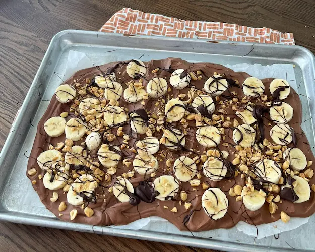 Chunky monkey yogurt bark on a baking sheet lined with parchment paper.