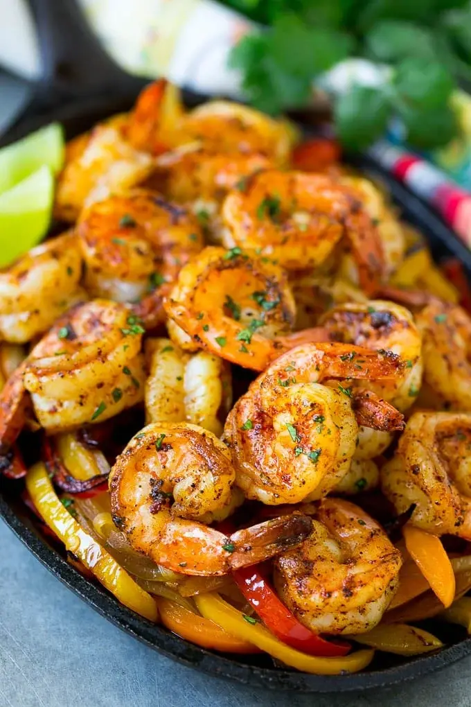 A hot sizzling plate of shrimp fajitas on a table.