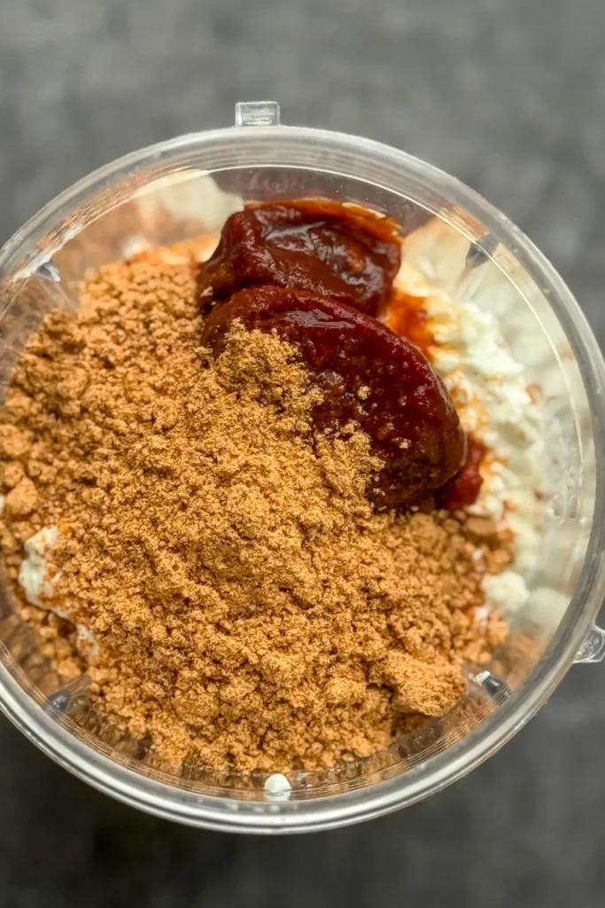 A birds-eye view of the cottage cheese, taco seasoning and chipotle peppers in a blender cup.