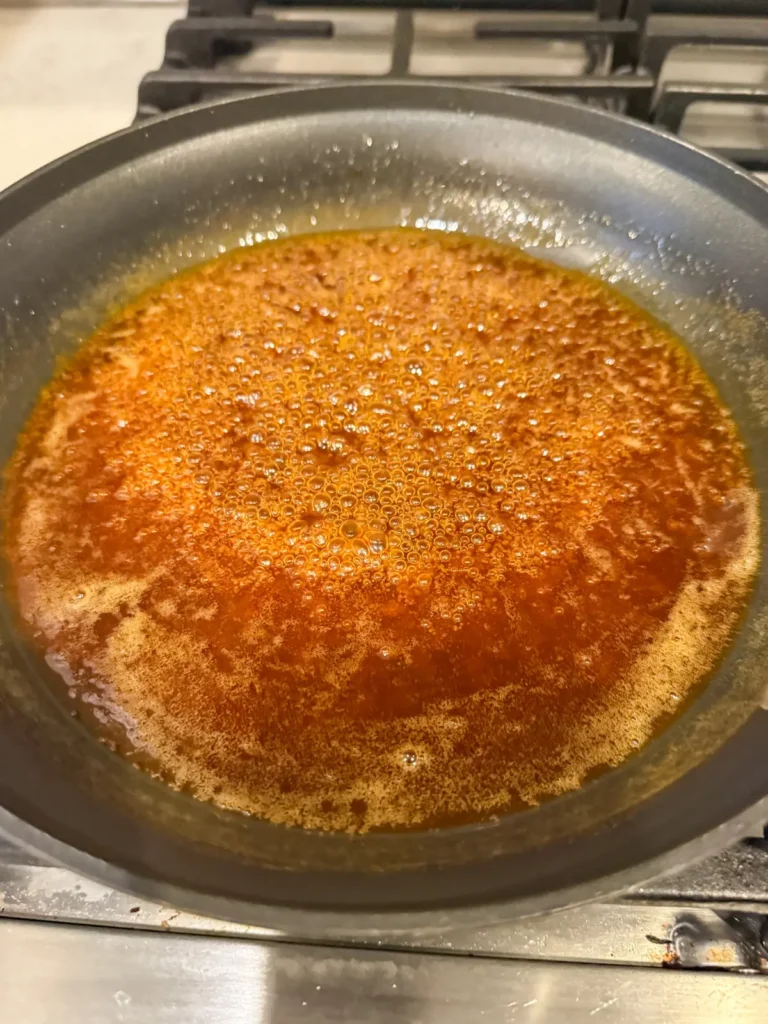 A pan with the honey sriracha sauce cooking on the stove.