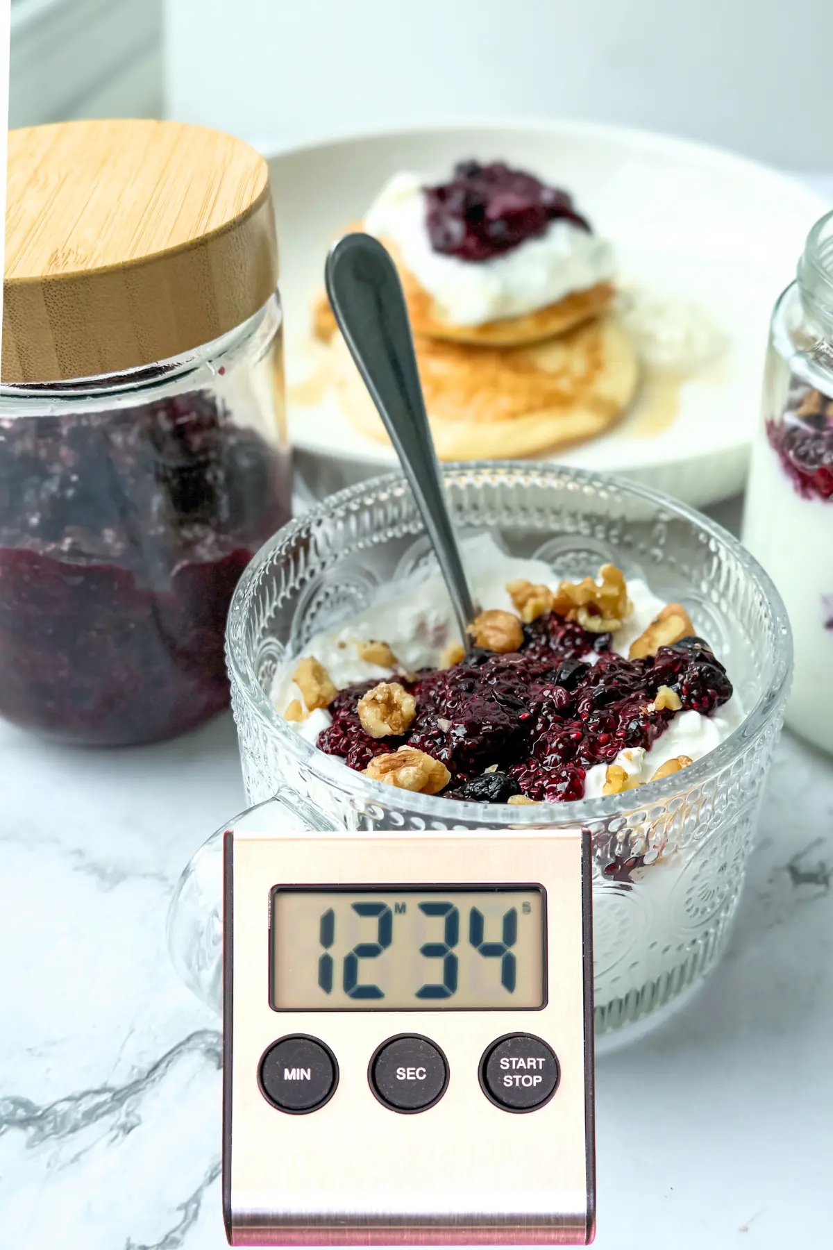 A stopwatch next to a table of food on it.