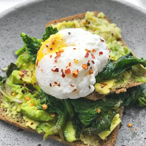 A nutrient dense meal for 18/6 intermittent fasting: avocado toast with a poached egg on a plate.