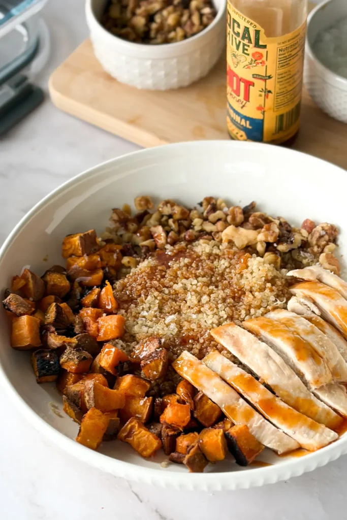 A fully assembled sweet potato bowl drizzled with honey sriracha on a counter.