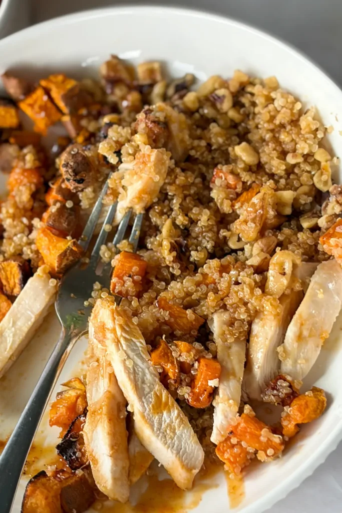 A sweet potato quinoa bowl mixed together in a bowl with a fork on it.