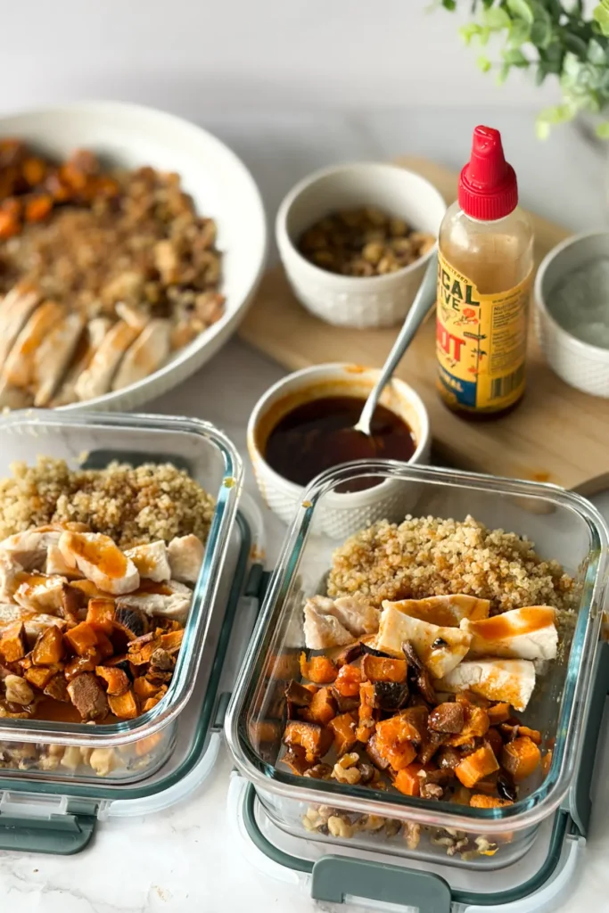 Two meal prep containers fully prepped next to a sweet potato bowl on a counter.