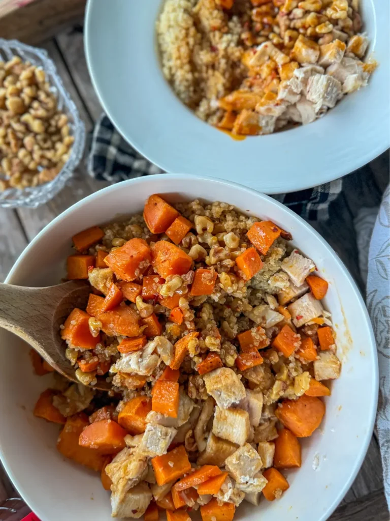 Two sweet potato and quinoa bowls mixed together on a table.