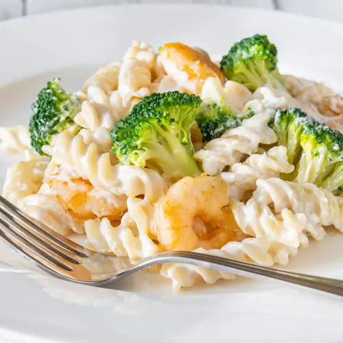Shrimp pasta with broccoli on a plate with a fork on it.