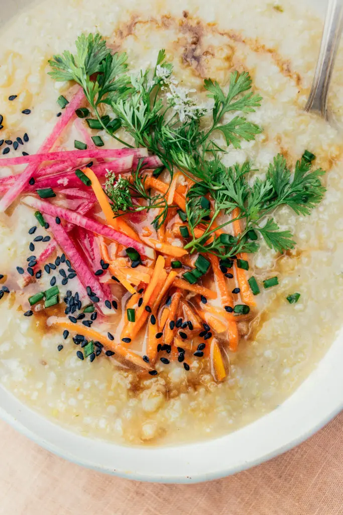 A bowl of dairy-free, gluten-free quinoa congee topped with sliced carrots and radishes.