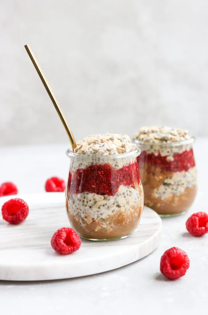 Two mason jars of peanut butter and jelly gluten and dairy-free overnight oats on a counter.