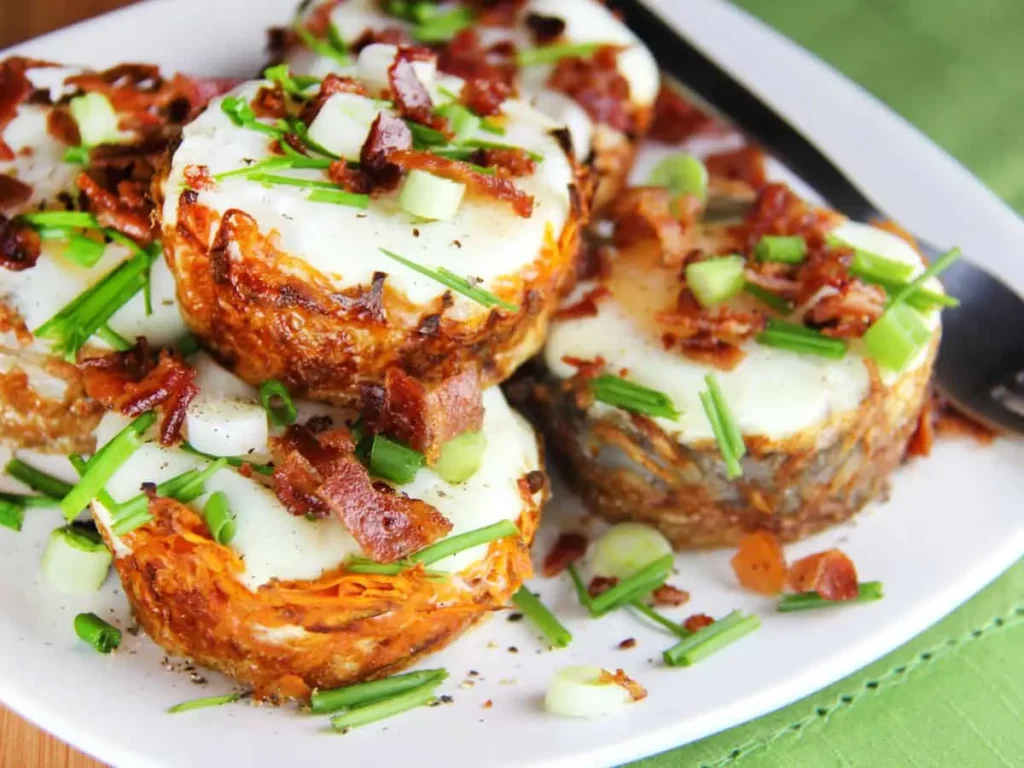 Sweet potato fritters topped with bacon on a plate.