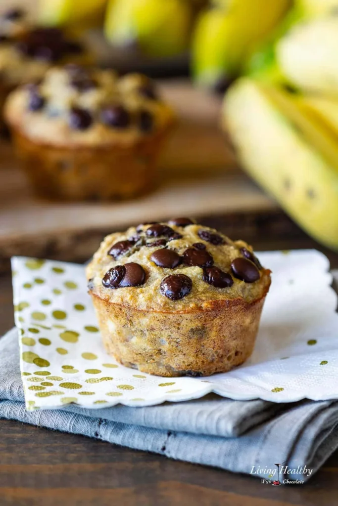 A coconut flour banana and chocolate chip muffin on a napkin on a counter.