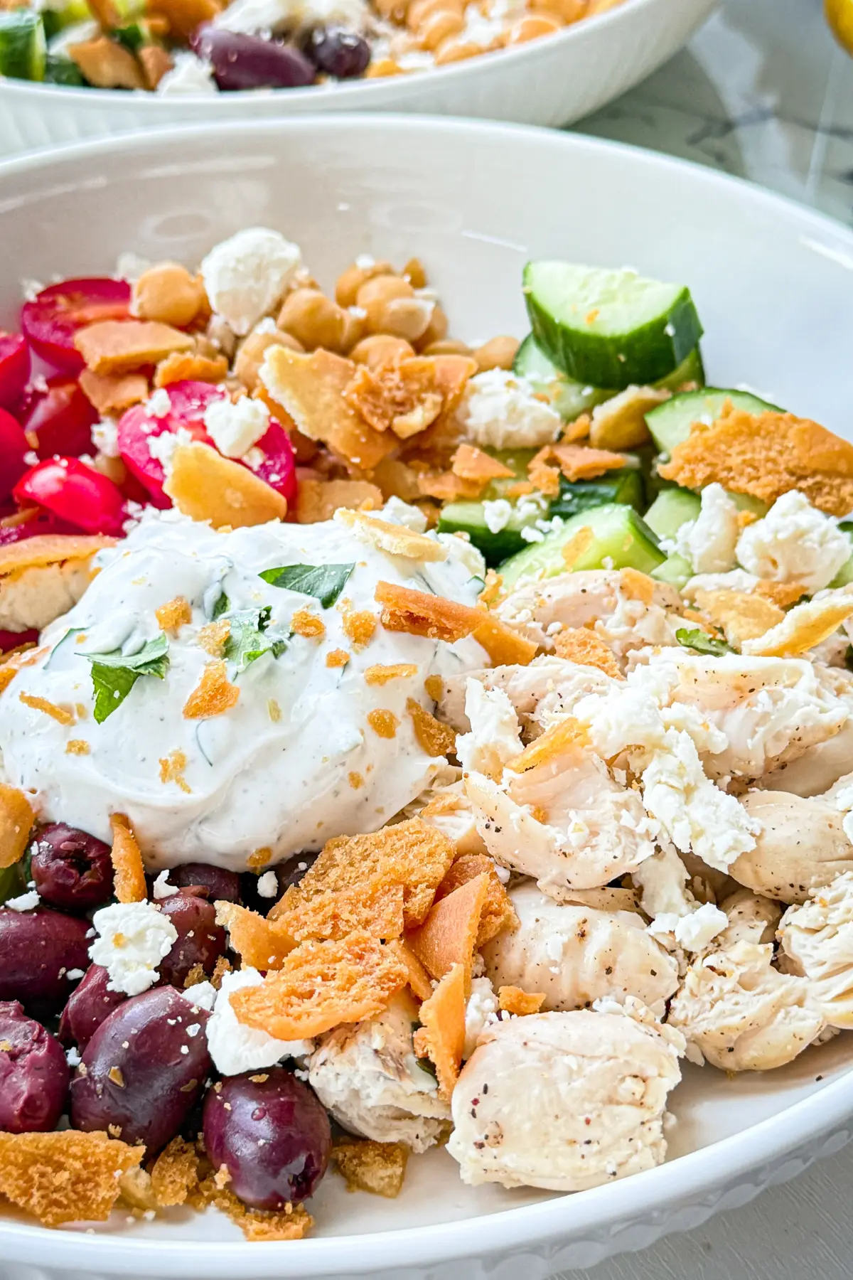 A close-up of a Mediterranean chicken and chickpea bowl with garlic yogurt sauce.
