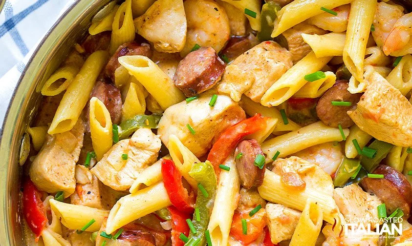 A pot full of pasta with sausage, veggies and noodles.