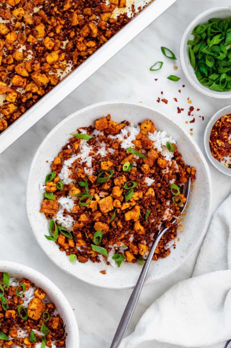 A birds-eye view of a bowl of ground tofu and veggies on a table.