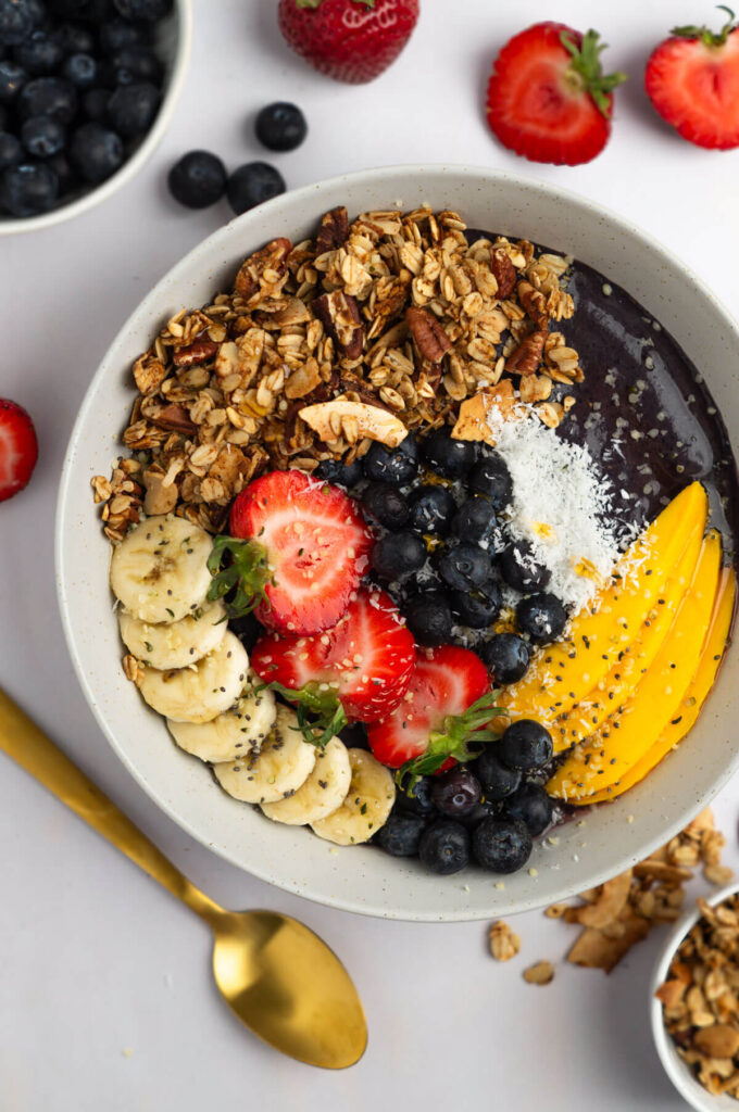 A fully assembled beautiful acai bowl with lots of fruit on a table.