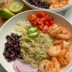 Two shrimp taco bowls next to a bowl of Greek yogurt avocado cream sauce on a counter.