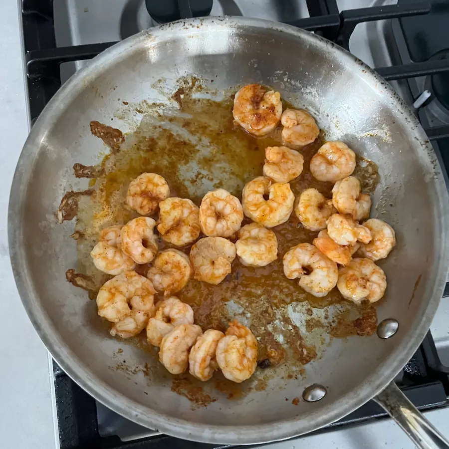 Seasoned shrimp in a pan, turning pink.