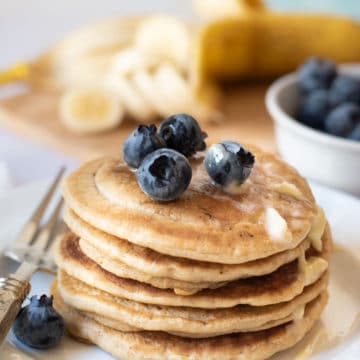 A stack of gluten-free pancakes topped with berries on a plate.