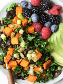 A close-up of black beans, sweet potatoes, and berries on a sheet pan.