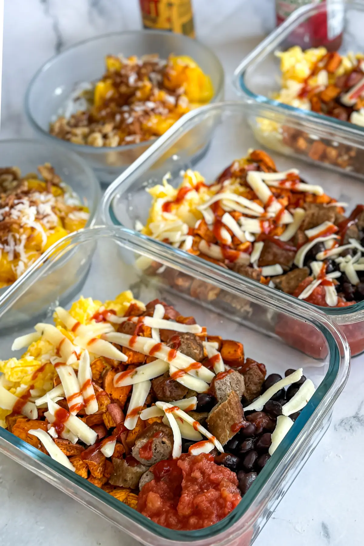 Roasted sweet potato scrambled egg bowls and chia mango bowls on a counter.