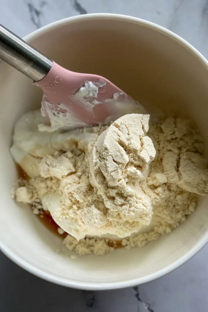 The cheesecake yogurt ingredients in a bowl with a spatula.