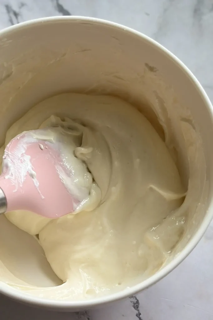 The cheesecake yogurt ingredients mixed together in a bowl, smooth and creamy.