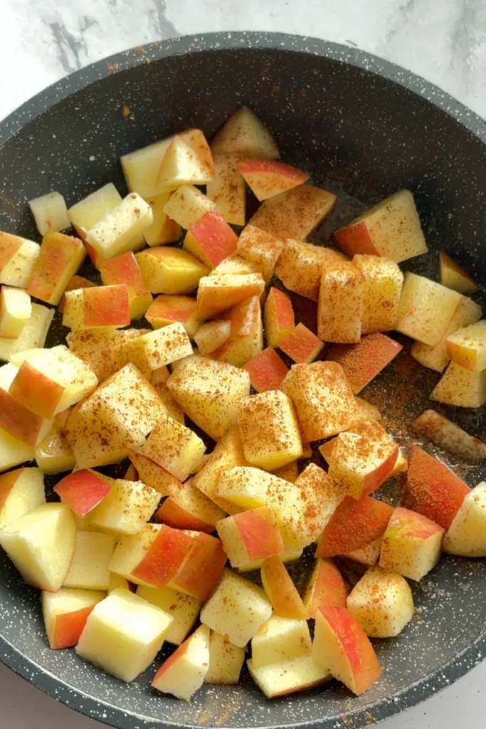 Cubed cinnamon apples in a pan.
