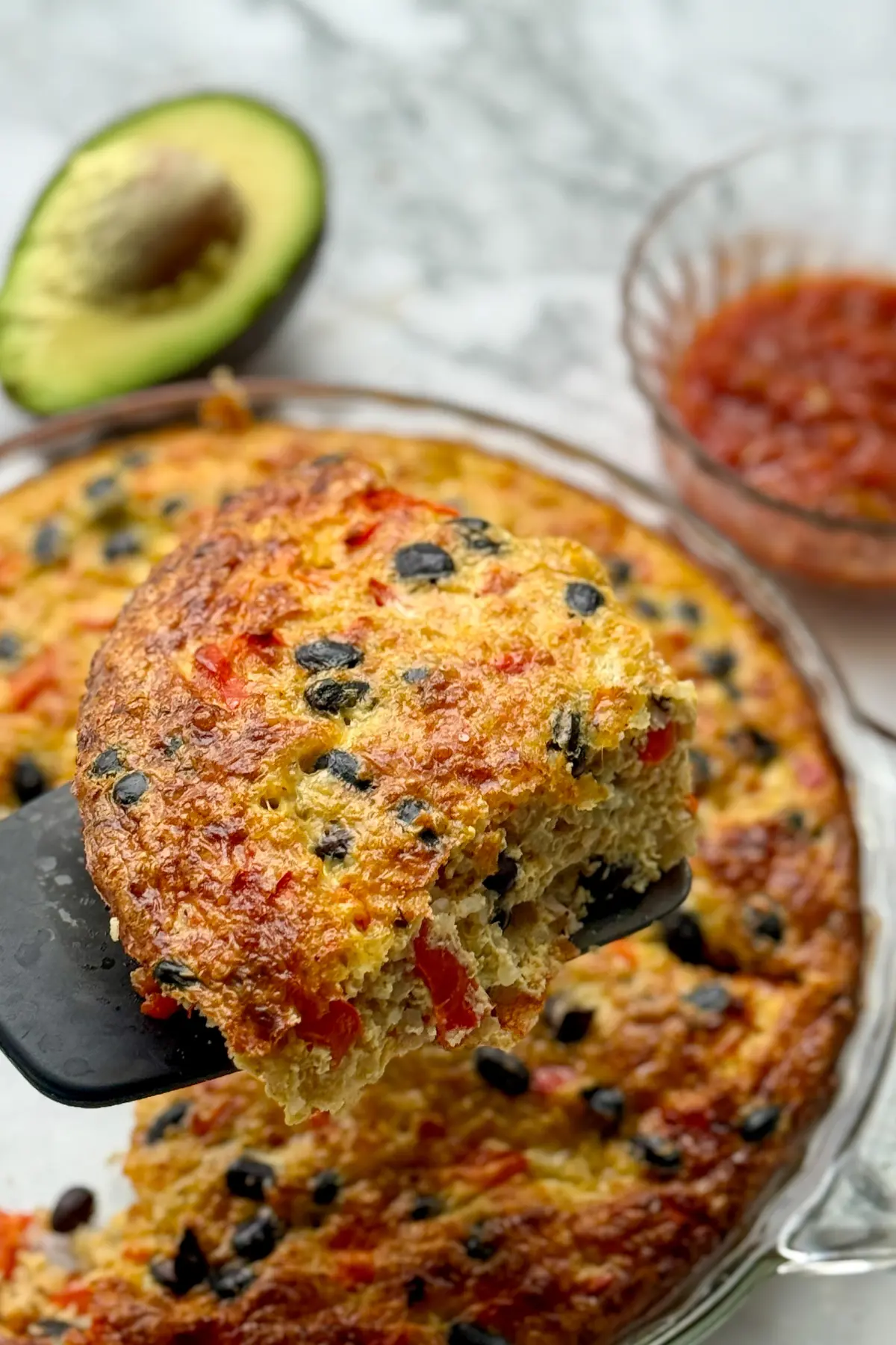 A spatula lifting a slice of savory quinoa breakfast bake out of the pan.