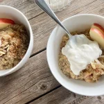 A quinoa chia breakfast bowl topped with the Greek yogurt and maple syrup mixture with a spoon in it.