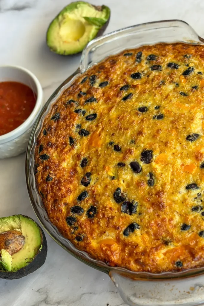 The breakfast bake right out of the oven on a counter next to salsa.