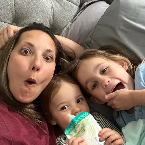 A mom laughing in bed with her two kids.