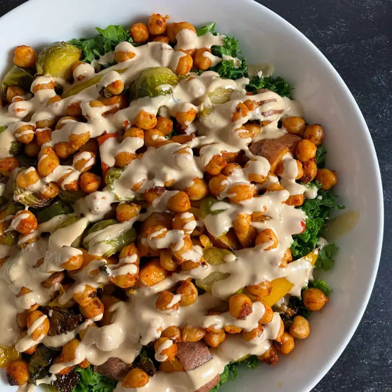 An Autumn harvest bowl with a creamy tahini drizzle on top in a white bowl.