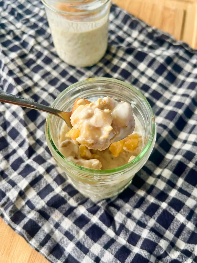 A creamy spoonful of caramelized apples overnight oats over a towel lined cutting board.