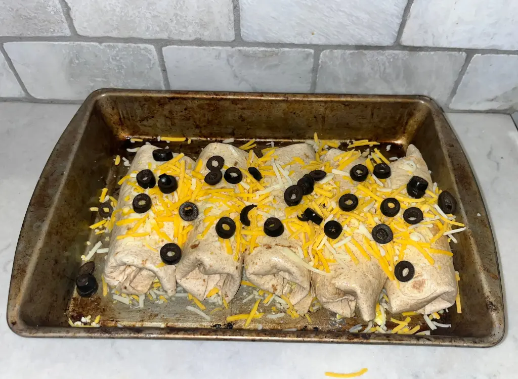 Assembled high protein breakfast burritos in a pan prior to baking in the oven.