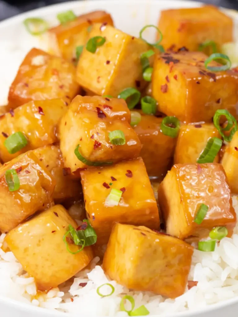 Crispy tofu with an orange sauce over a bed of rice.