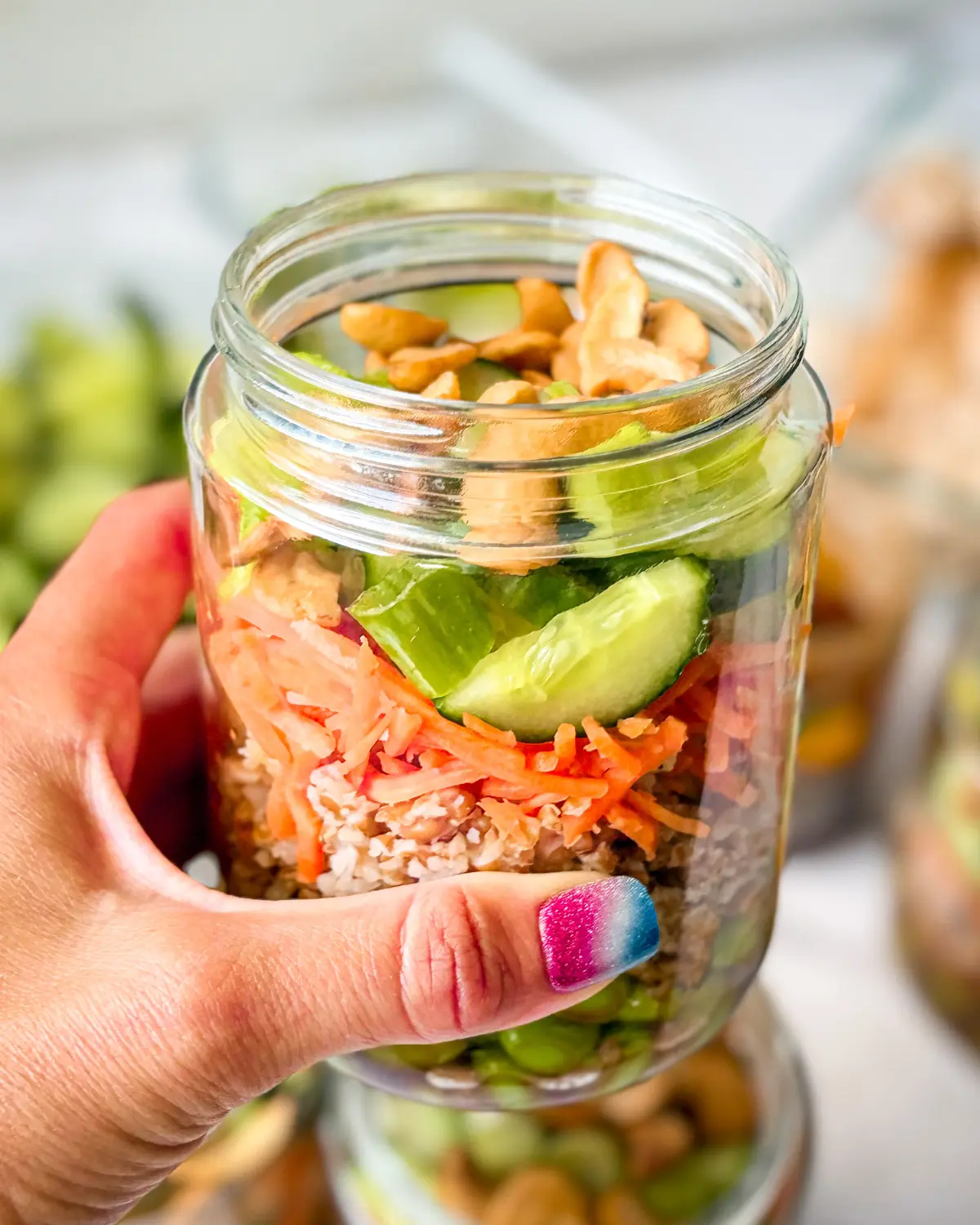 Someone holding up a cashew crunch salad jar.
